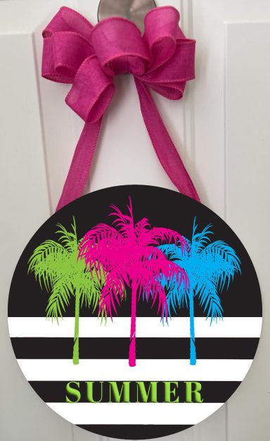 Colorful summer sign featuring palm trees and a pink bow against black and white stripes.