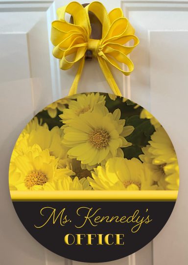 Round sign reading "Ms. Kennedy's OFFICE" with a yellow floral background and ribbon.