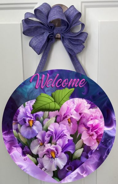 Round floral welcome sign featuring purple and pink irises with a bow at the top.