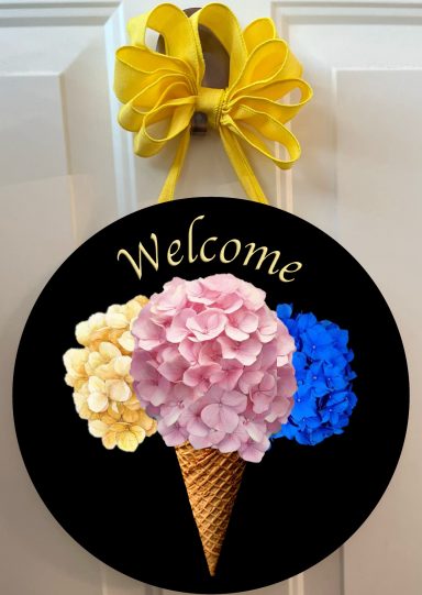 Round welcome sign featuring an ice cream cone with three scoops: yellow, pink, and blue.